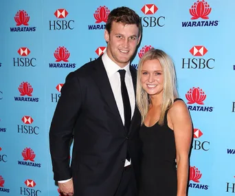 Two people smiling at an event with a blue HSBC and Waratahs backdrop.