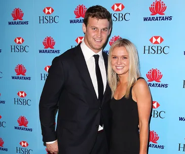 Two people smiling at an event with a blue HSBC and Waratahs backdrop.