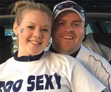 A smiling couple with the woman wearing a shirt that says "TOO SEXY" and a paw print sticker on her cheek.