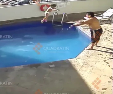A child jumps into a swimming pool as an adult stands nearby, reaching out.
