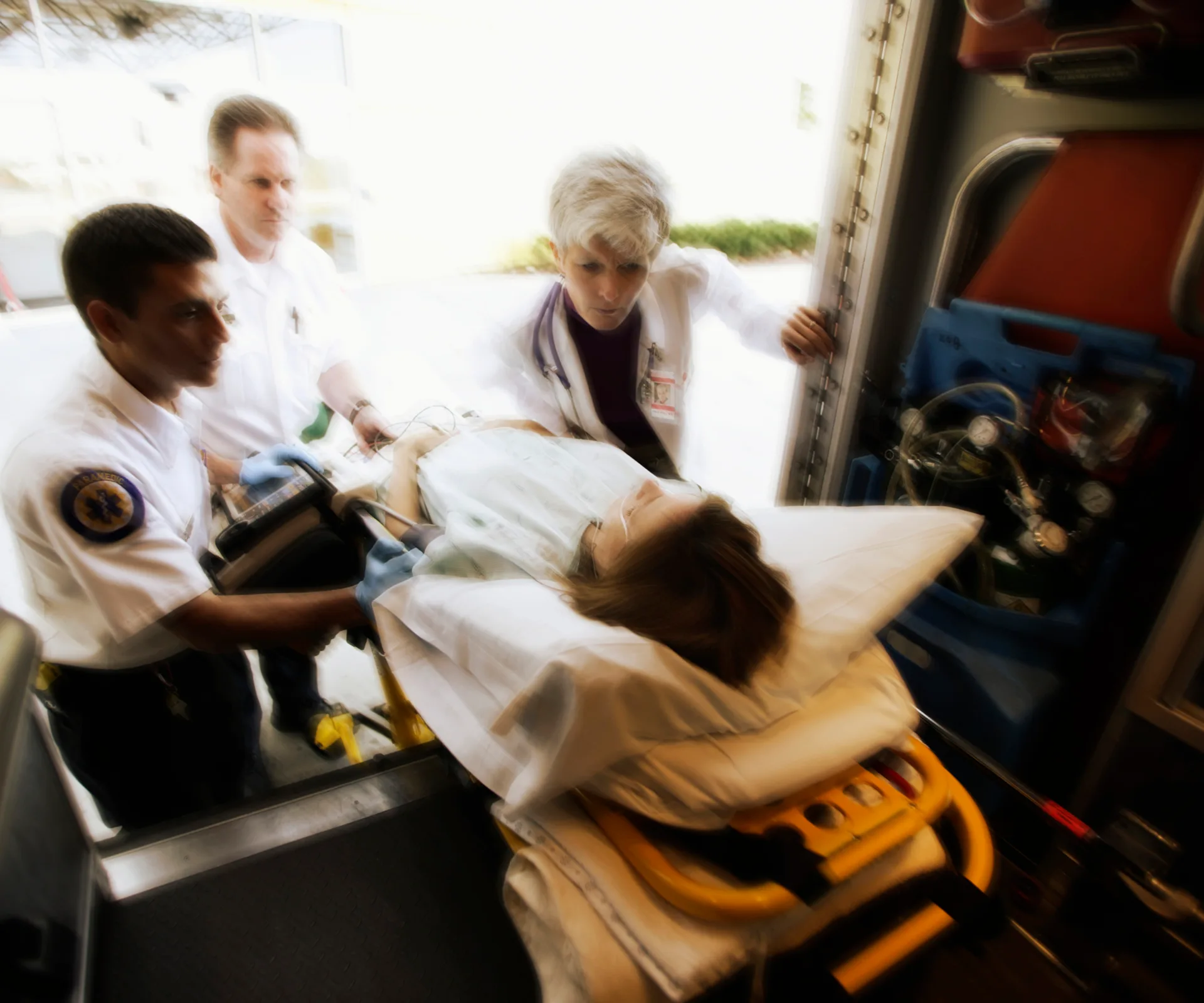 Paramedics and a doctor attend to a patient on a stretcher inside an ambulance.