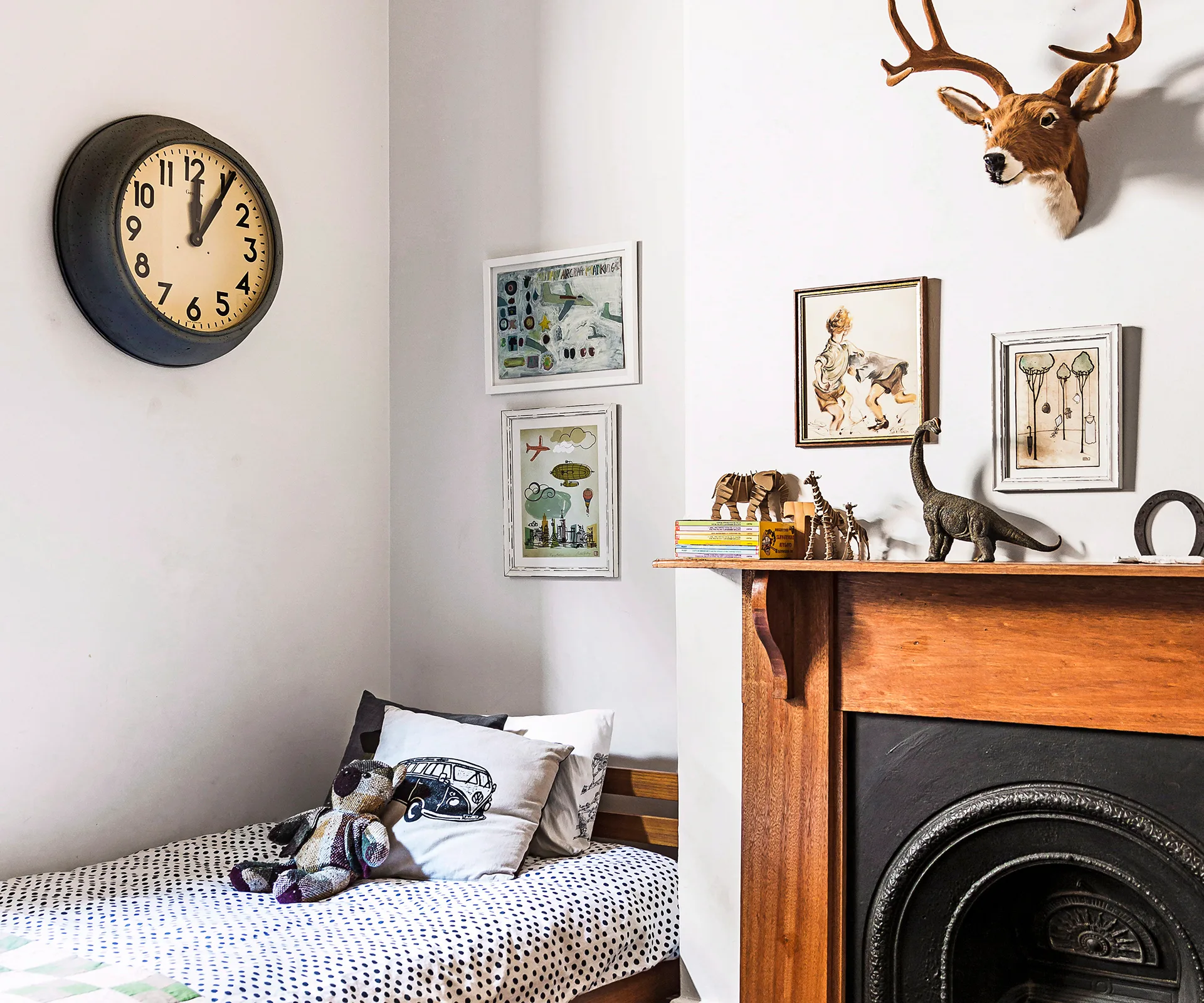 Cozy child's bedroom with toy animals, framed art, and a decorative deer head above a wooden mantle.