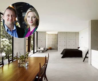 Dining area in a modern minimalist mansion with a bedroom, featuring floor-to-ceiling windows and concrete walls.