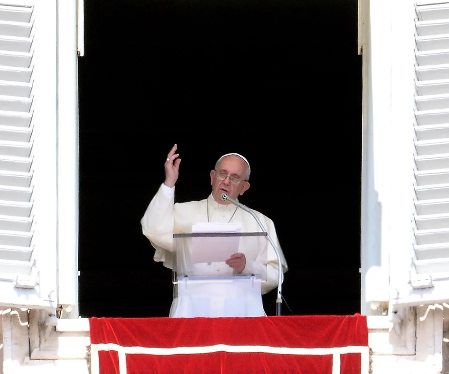 Pope delivering a speech from a window, gesturing with hand, wearing white robes and zucchetto.