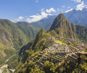 View of Machu Picchu ruins with mountains and blue sky in the background.