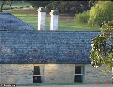 Old brick building with two visible windows, and trees in the background at Port Arthur, Tasmania.