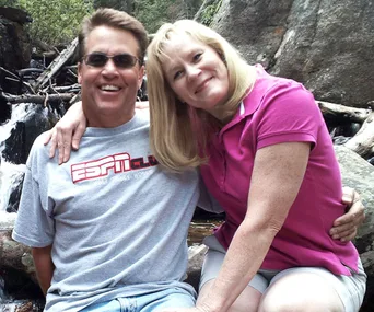 A couple sitting on rocks near a waterfall, smiling at the camera.