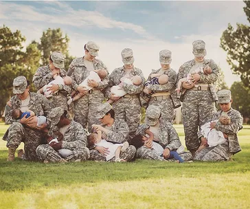 Soldiers in uniform seated and standing, breastfeed their babies outdoors.