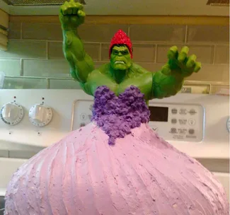 A Hulk figure in a purple and pink dress modeled as a cake on a kitchen stovetop.