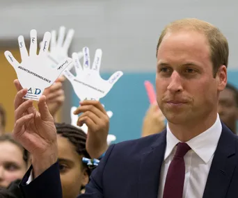 Prince William holding a paper hand with messages at an event promoting mental health awareness.