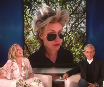 "Ellen and Portia on a talk show, showing a large screen with Portia's photo on a bad hair day, both laughing."