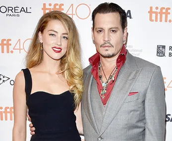 A man in a grey suit with a red shirt and a woman in a black dress at TIFF event.
