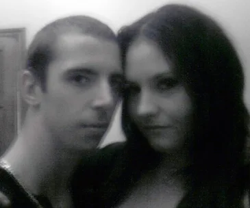 A black and white photo of a couple posing closely together, looking at the camera with neutral expressions.