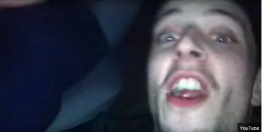 Selfie of a young man with an open mouth expression in a dark environment, captured from a video.