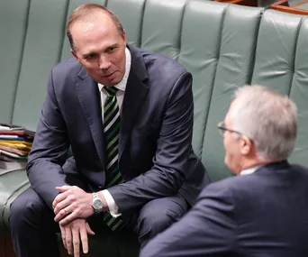 Two men in suits having a discussion while seated in a professional setting.