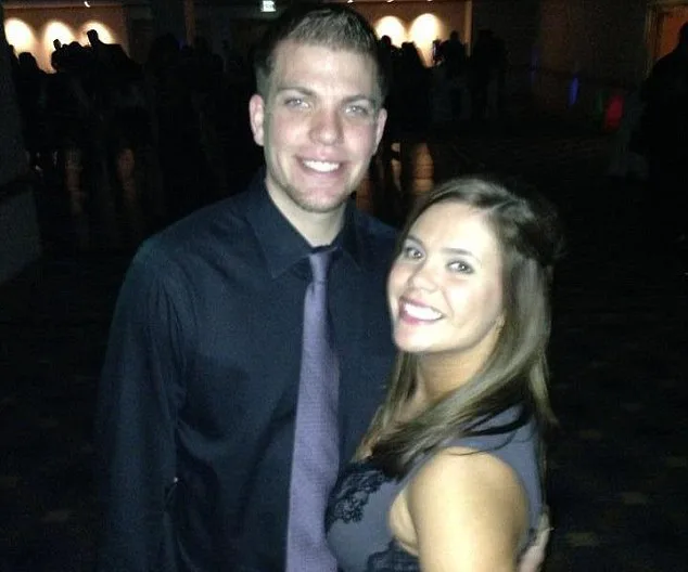 A smiling couple posing together in dark formal attire at an event.