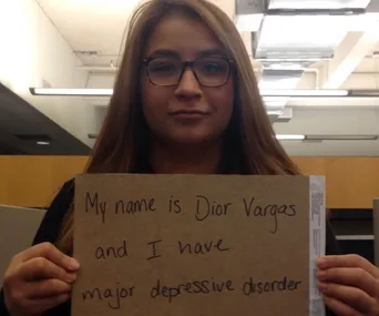 Young woman holding a sign stating her name and that she has major depressive disorder, emphasizing awareness of mental illness.