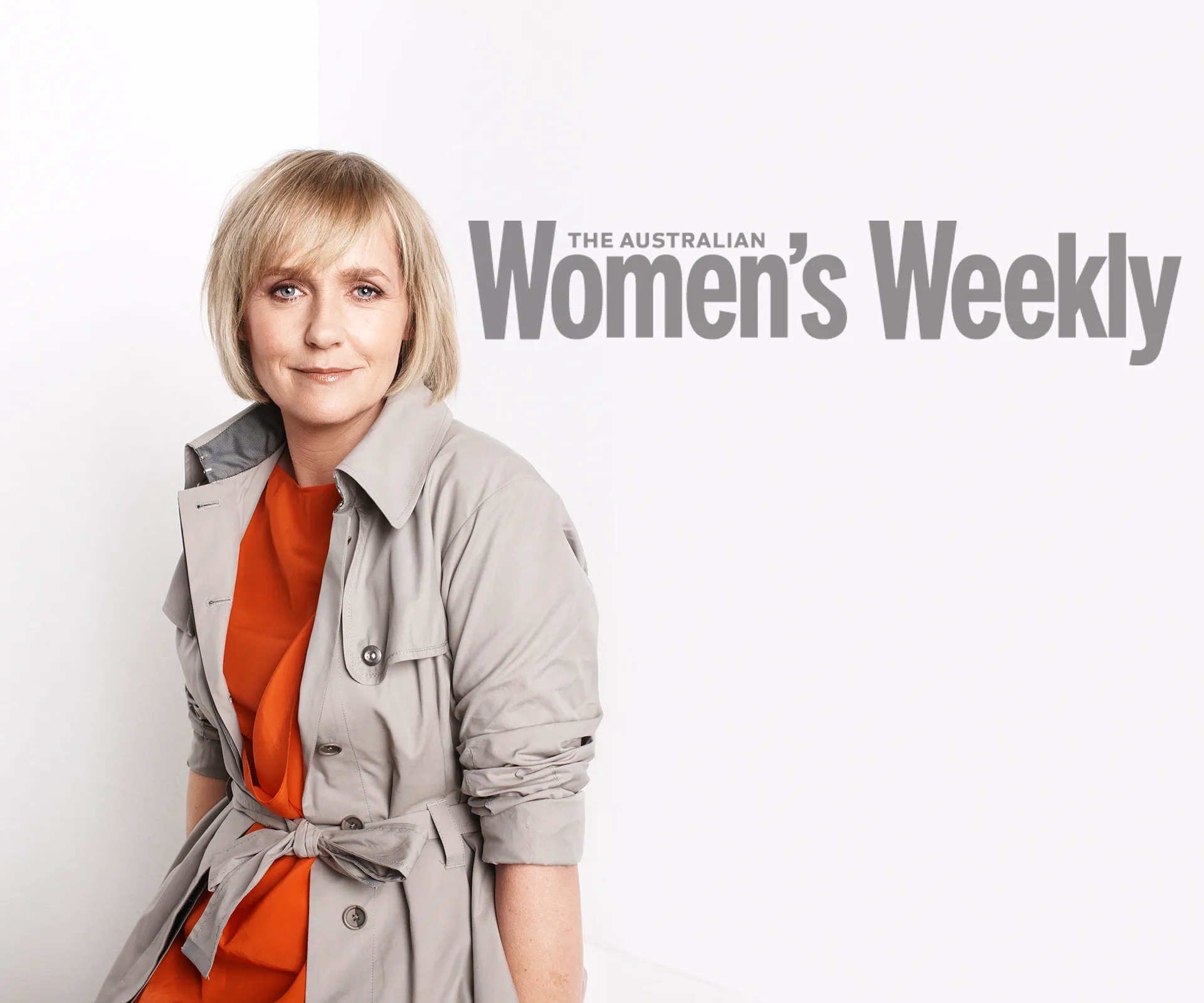 Female in gray coat over orange top, sitting against a white background, "The Australian Women's Weekly" text behind.