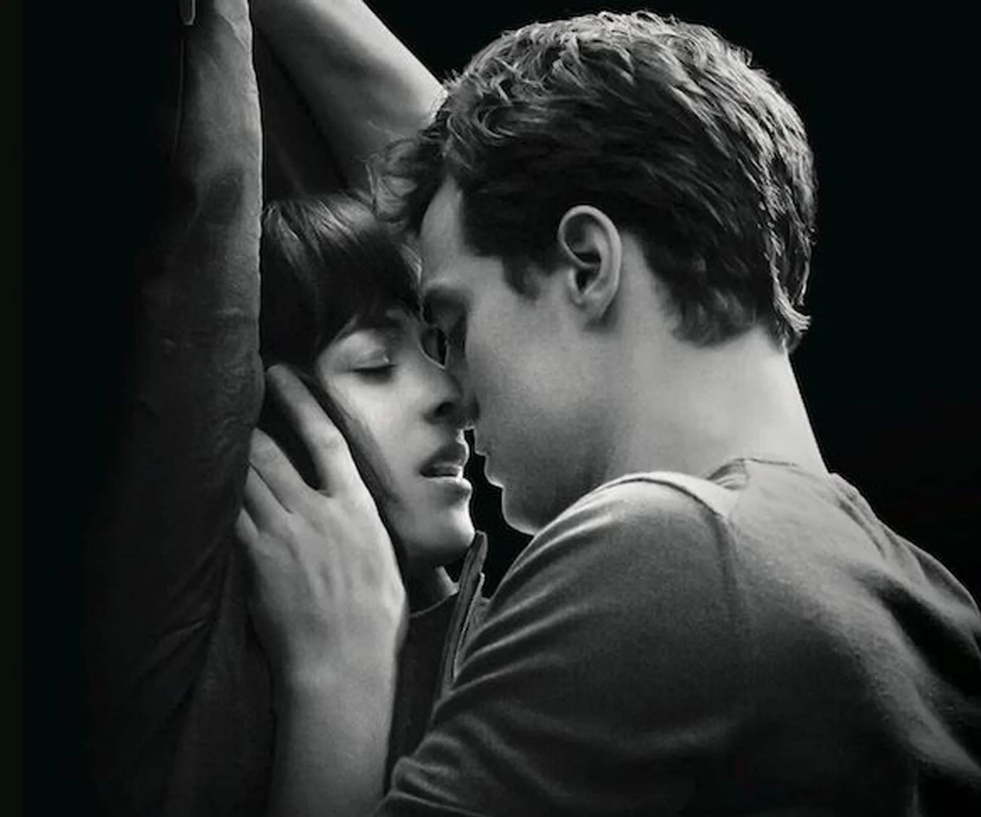A B&W close-up of a couple in an intimate embrace, with the woman’s arms raised and their faces close together.