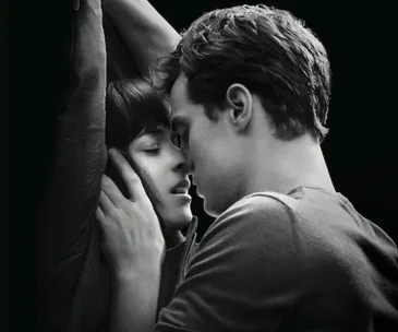 A B&W close-up of a couple in an intimate embrace, with the woman’s arms raised and their faces close together.
