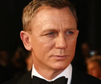 "Close-up of a man with short hair, wearing a tuxedo, looking serious."