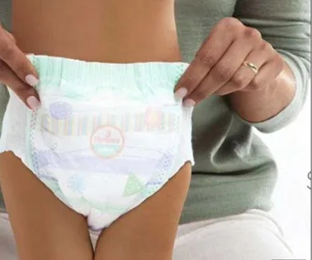 Toddler shown in a diaper, held by an adult's hands.