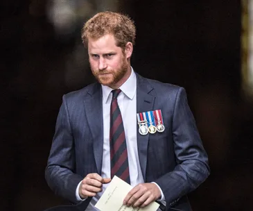 Man in suit with medals on jacket, holding a program, looking serious.