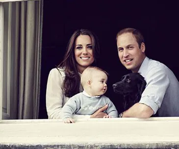 Family with a baby and a black dog looking out of a window.