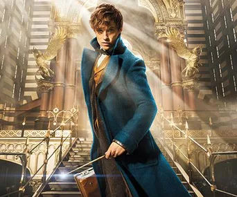 Eddie Redmayne as Newt Scamander, in a blue coat, holding a suitcase inside a grand hall with ornate details.