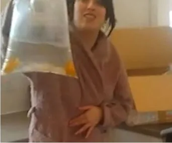 Woman holding a bag of live fish with a surprised expression, standing next to an open cardboard box.
