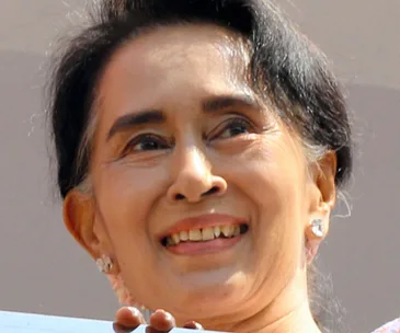 A smiling woman with short, dark hair, looking upwards, wearing earrings.
