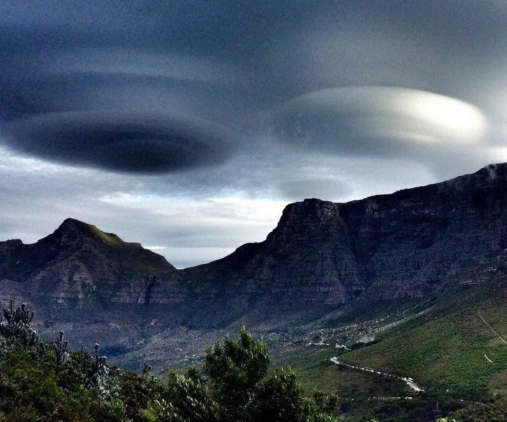 UFO-like lenticular clouds hover over mountains in Cape Town, creating a dramatic and mysterious sky.