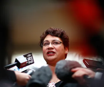 A woman speaking passionately at a press conference, surrounded by microphones.