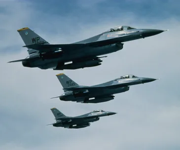 A formation of three fighter jets in flight against a blue sky.