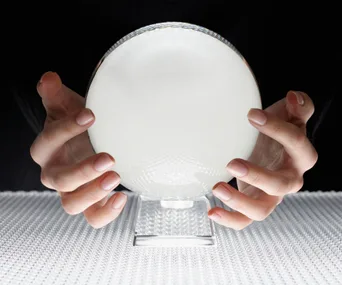 Hands holding a glowing crystal ball on a textured surface.