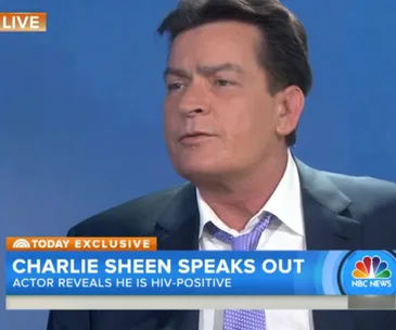 Charlie Sheen on NBC News, discussing his HIV-positive status, wearing a suit and open-collared shirt.