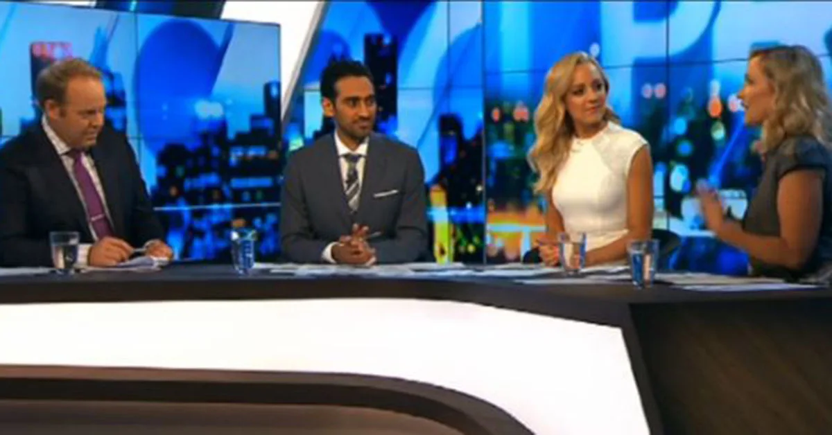 Panel sitting at a news desk with a cityscape background.