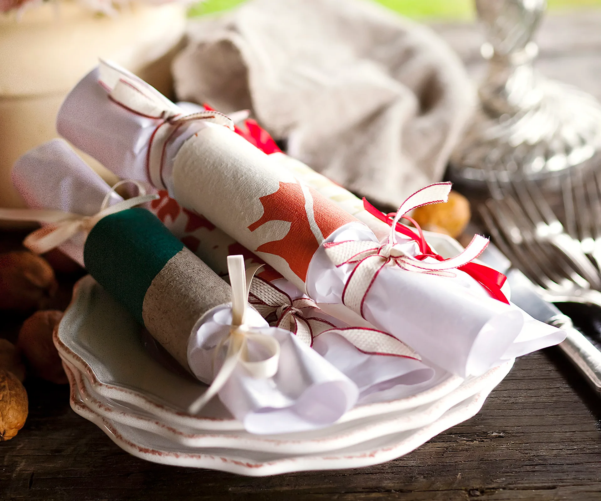 Rustic homemade Christmas bonbons wrapped in festive paper and tied with ribbons on stacked plates.