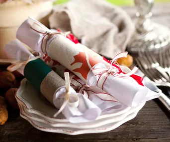 Rustic homemade Christmas bonbons wrapped in festive paper and tied with ribbons on stacked plates.