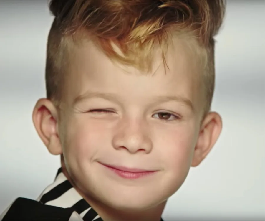 Young boy smiling and winking at the camera in an advertisement.