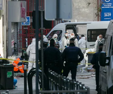 Police and forensic team at crime scene in Paris, gathered around van, wearing protective gear and investigating.