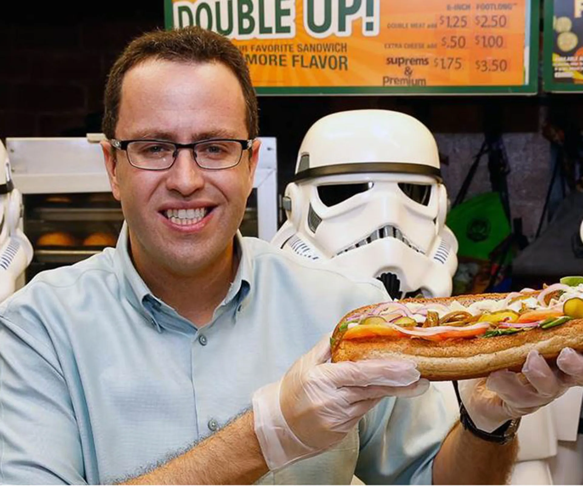 Man holding a Subway sandwich with Stormtrooper helmets in the background.