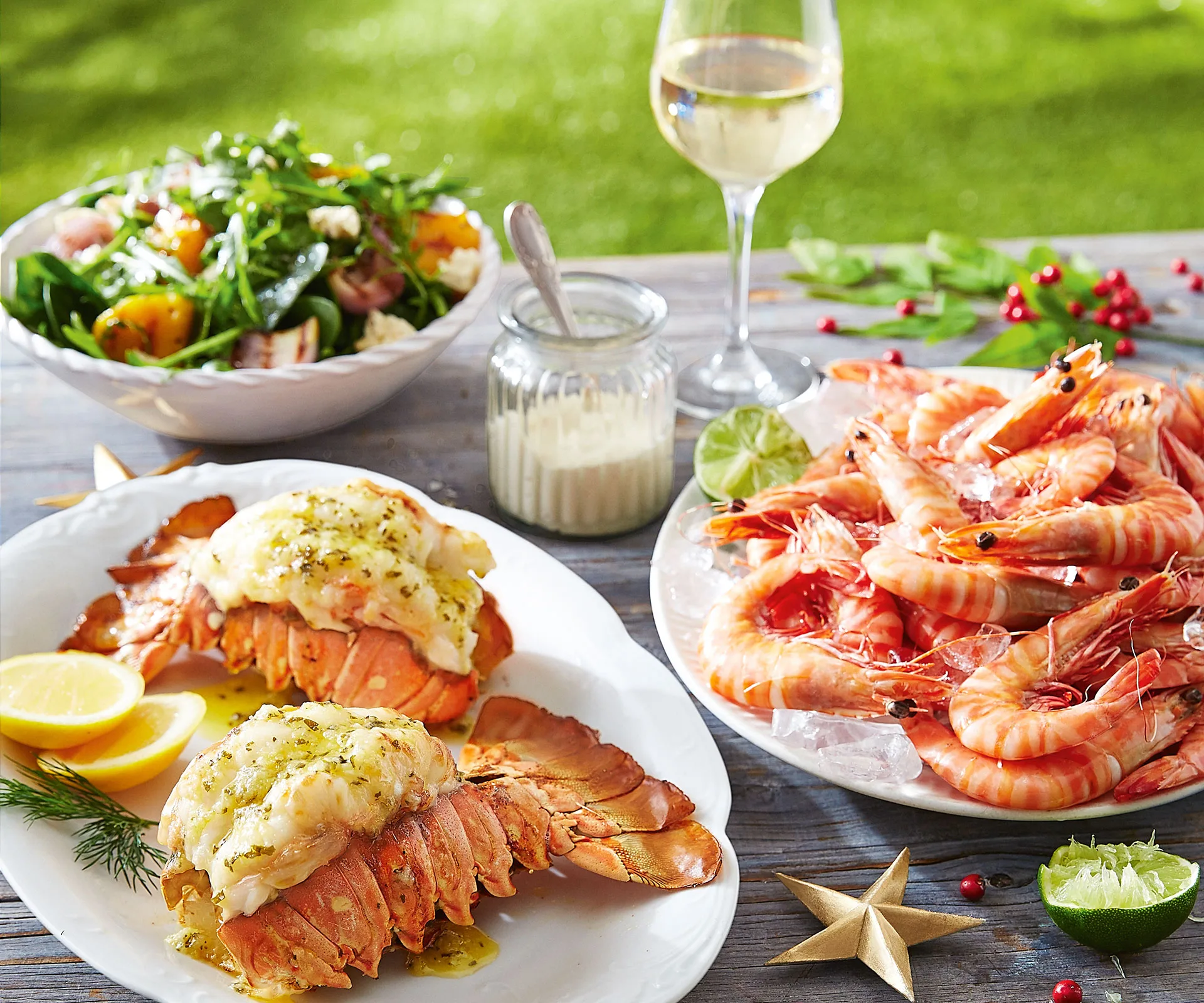 Seafood Christmas spread with lobster, prawns, salad, and a glass of white wine on a festive table setting.