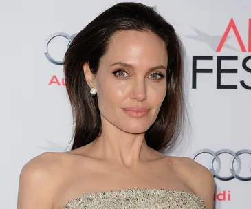 A woman with long hair in an elegant dress poses on the red carpet.