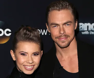Two smiling individuals at a "Dancing with the Stars" event, posing against a branded backdrop.