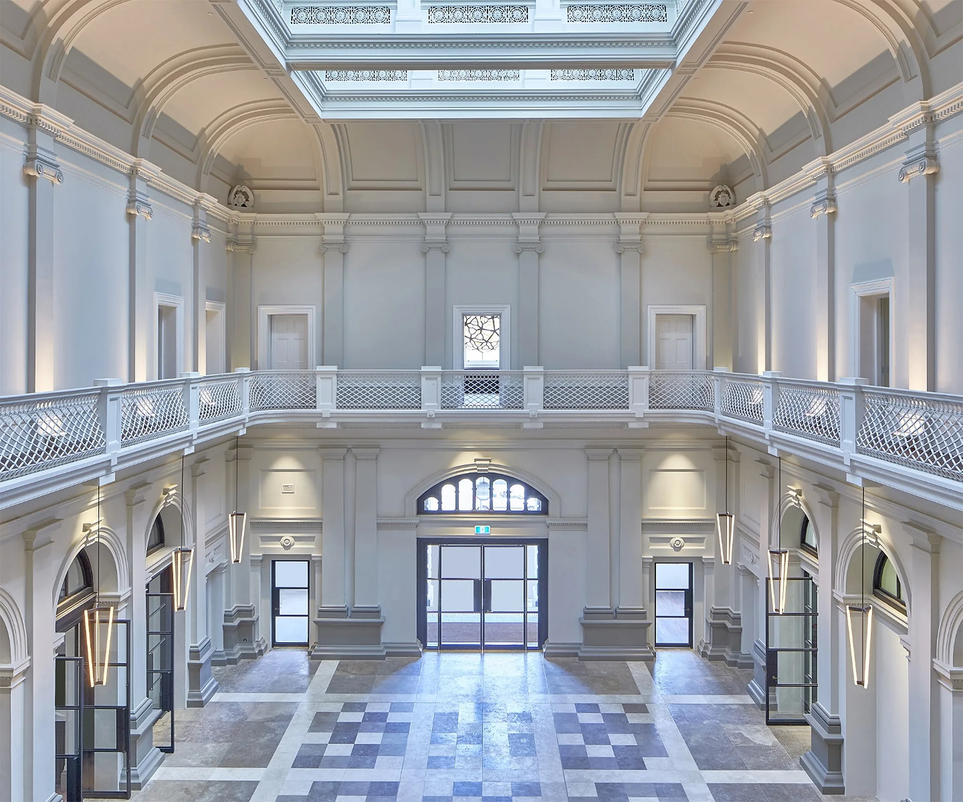 Spacious grand hall interior with archways, checkered floor, and upper level balcony.