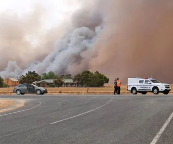 Police vehicle and officers by a road with smoke from South Australian fires in the background.