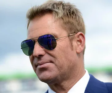 Man wearing sunglasses, with a reflection of another person visible in the lenses.