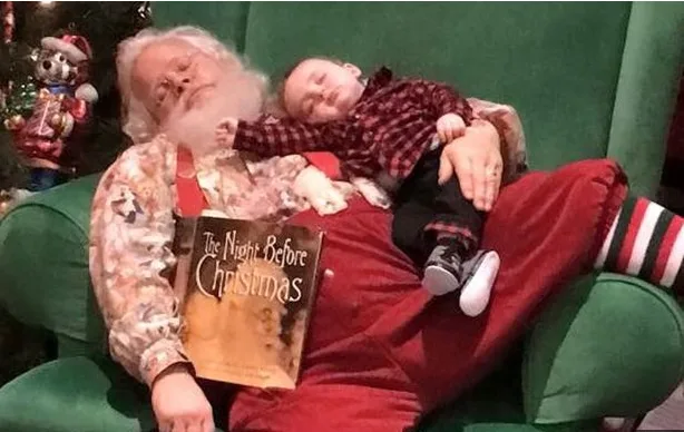 Sleeping Santa and baby on green chair with "The Night Before Christmas" book.