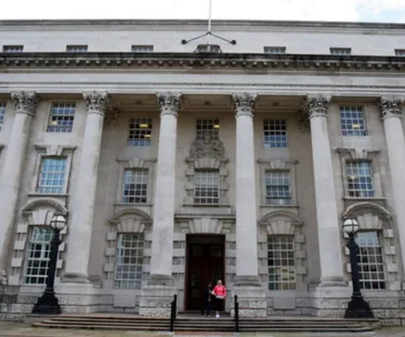 Front view of Belfast High Court building with columns and two people by the entrance.